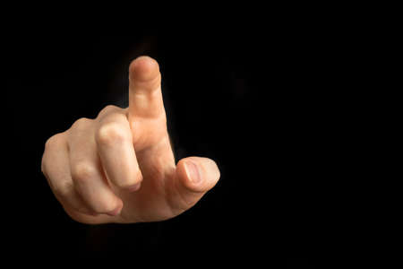 Hand pointing gesture on empty space on a black backgroundの写真素材
