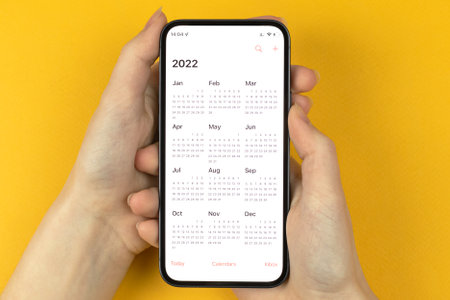 Calendar 2022 app on smartphone screen. Hand with mobile phone. To do, new year planning conceptの写真素材