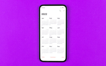 Smartphone with calendar 2022. Business workspace, purple background. Top view