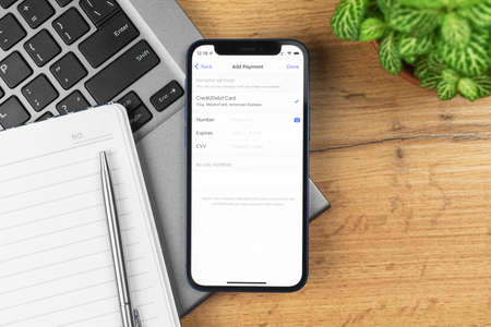 Kharkov, Ukraine - November 21, 2021: Add Payment Method screen on Apple iPhone, mobile phone debit card settings. Business workspace, wooden table, top viewのeditorial素材