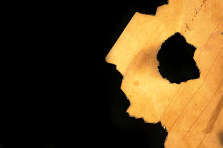 Burned peice of old paper on a black background. Vintage and retro design photoの写真素材