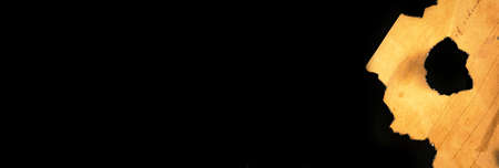 Banner, burned peice of old paper on a black background. Vintage and retro design photoの写真素材