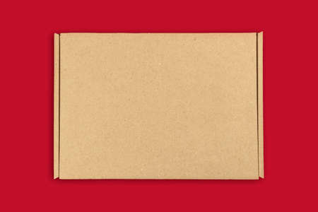 Brown cardboard box mockup, top view. Christmas gifts concept. Red table background. Shipping and delivery, copy spaceの写真素材