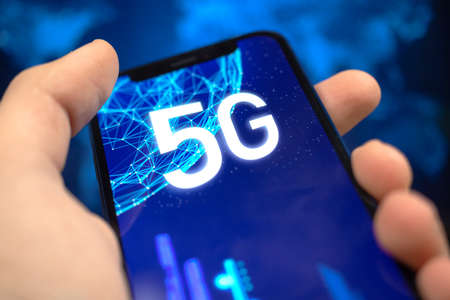 Man uses smartphone with 5G network connection. Future of high speed mobile internet, global wireless technology backgroundの写真素材
