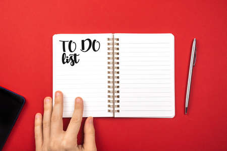 Notebook with to do list. Planning for new year concept. Red background, silver pen, copy space and top viewの写真素材