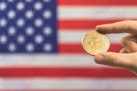 Close-up bitcoin coin and American flag background. Cryptocurrency and United States of America conceptの写真素材