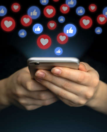 Social media concept. Hands using smartphone with like notification icons. Social networking, black backgroundの写真素材