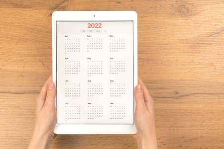 2022 calendar on tablet computer screen. Business wooden table desktop background. Concept of...