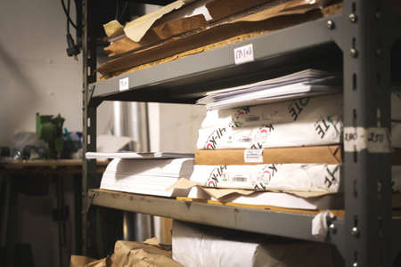 Printing house warehouse and metal shelf with different type of paper. Working process, printing industry concept photoの写真素材