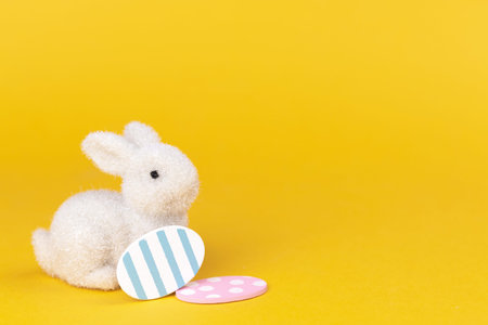 Easter bunny with colorful easter eggs on a bright yellow background. Spring holiday postcard concept, copy spaceの写真素材