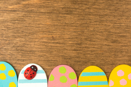 Colorful Easter eggs bottom border, old rustic wood background, flat lay design, top view with copy...