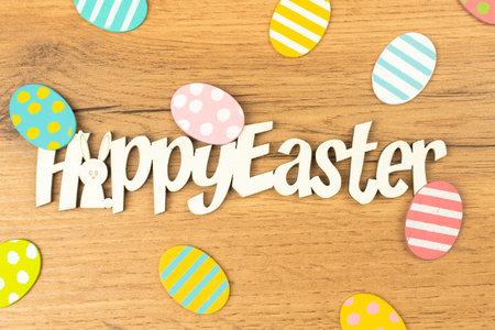 Happy easter celebration text and words with easter eggs on a wooden background. Spring holiday...