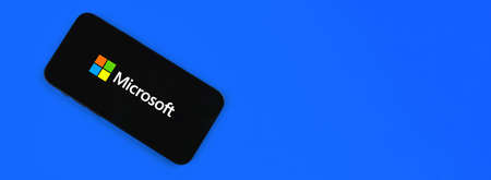 Kharkov, Ukraine - January 19, 2021: Microsoft on blue background, web banner with copy space. Software company icon on a mobile phone screen, top viewのeditorial素材