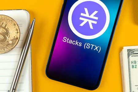 Stacks STX coin symbol. Trade with cryptocurrency, digital and virtual money, banking with mobile phone concept. Business workspace, table with laptop top view photoのeditorial素材