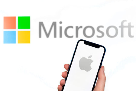 Apple and Microsoft . Hand with mobile phone, business concept photo