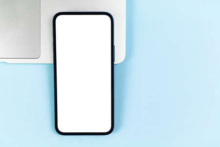 Flat lay smartphone mockup, office desktop with laptop, bright blue background. top view, copy spaceの写真素材