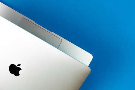 Apple Macbook Air with M1 on bright blue table background. Business and office concept, top view, flat layのeditorial素材