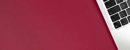 Modern laptop keyboard flat lay burgundy banner background. Office workplace table, minimal design concept. top view, copy spaceの写真素材