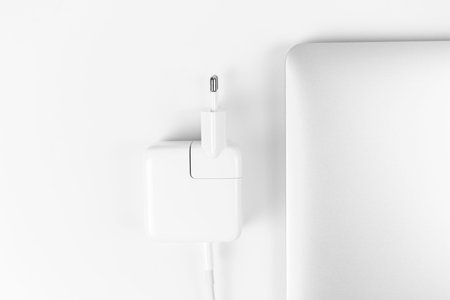 Charging battery laptop. Modern and fast USB C charger with silver laptop on office desktop, top...
