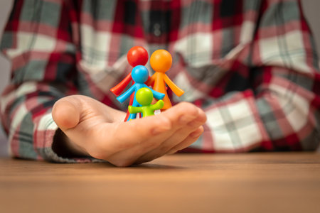 Figurines of family in human hand. Concept of family values, continuation and insurance. caring...