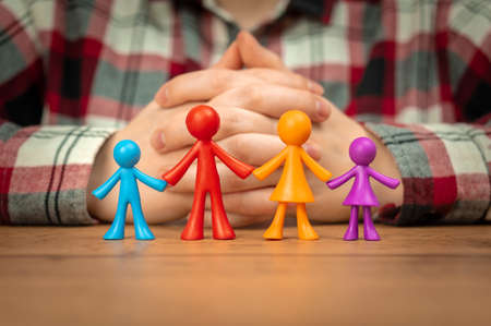 Family insurance concept with colorful family figurines on wooden tableの写真素材