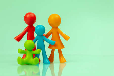Young family figurines on bright background. Concept of parenting, caring for childrenの写真素材