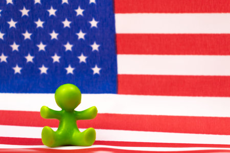 American family concept with plastic figurines of kid standing on USA flag. Patriot background