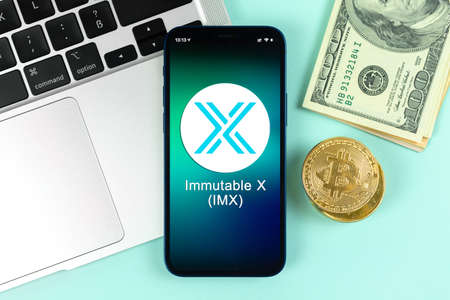 Kharkov, Ukraine - January 31, 2022: Immutable X IMX coin symbol. Trade with cryptocurrency, digital and virtual money, banking with mobile phone concept. Business workspace, table with laptopのeditorial素材