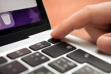 Kharkov, Ukraine - February 9, 2022: Hand pressing fingerprint scanner key on modern laptop keyboard. Fingerprint button closeupのeditorial素材