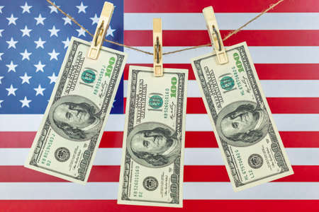 Concept of money laundering. USA Illegal financial business concept, American dollar banknotes hanging on a rope. Corruption and crime, flag background photoの写真素材