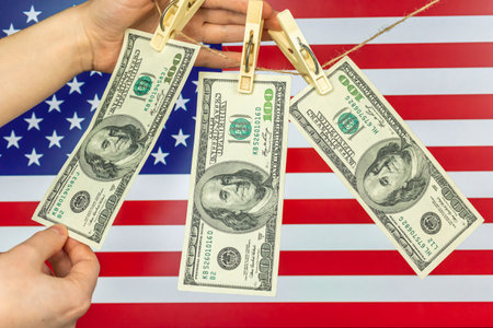 Hands and money laundering. USA Illegal financial business concept, American dollar banknotes hanging on a rope. Corruption and crime, national flag background photoの写真素材
