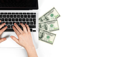 Freelancer working on laptop and making money, us dollars on white table, top view