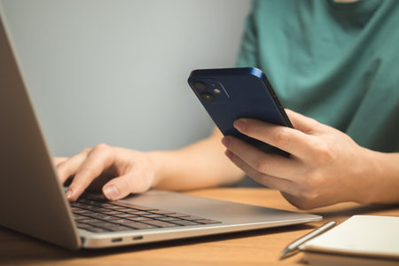 Laptop on wooden desk and young woman hand on keyboard. Freelance workplace, work from home concept backgroundの写真素材