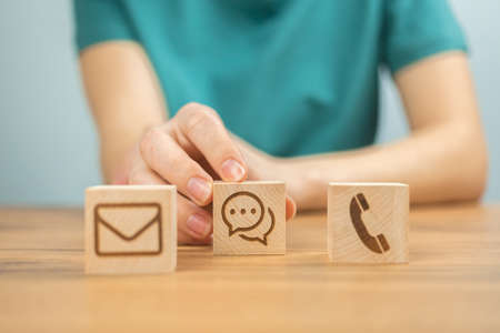 customer service concept background. Call center, assist and support, cooperation. Wooden cubes with message icons and young woman hands in office photoの写真素材