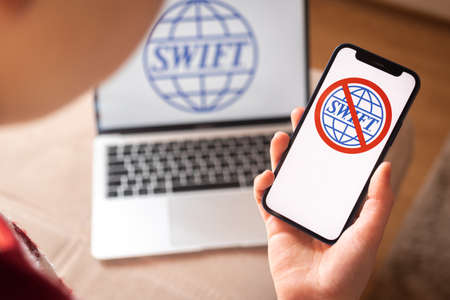 Kharkov, Ukraine - February 27, 2022: SWIFT blocked,  close-up on mobile phone screen. Girl use SWIFT banking and international technology concept photoのeditorial素材