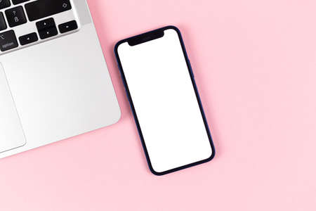Flat lay Apple iPhone screen mockup, office desktop with laptop, bright pink background. Top view, copy space photoのeditorial素材