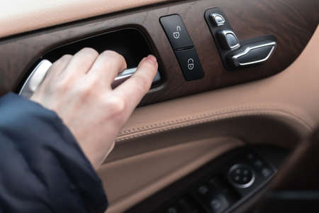Hand with car door handle inside the luxury car interior with leather and wood design. close-up viewの写真素材