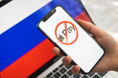 Poltava, Ukraine - March 23, 2022: Apple pay and Russia flag. Sanctions, ban and banned business. Apple pay stopped working in Russian Federation, logo close-up photoのeditorial素材