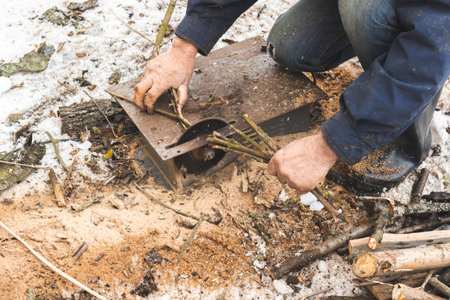 Man cutting wood using stationary circular saw outdoors in winter for kindling close-up