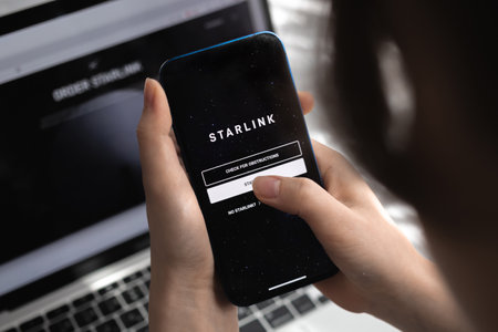 Poltava, Ukraine - March 26, 2022: Woman using Starlink app on mobile phone, Elon Musk Internetのeditorial素材