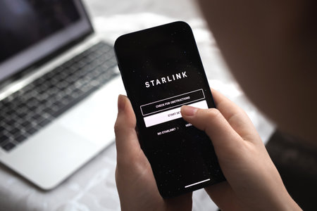 Poltava, Ukraine - March 26, 2022: Person using Starlink on smartphone, logo close-up view photoのeditorial素材