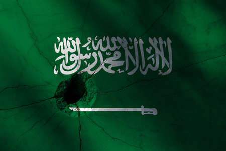 Saudi Arabia flag with big crack or bullet hole. Military conflict and war in country concept background photoの写真素材
