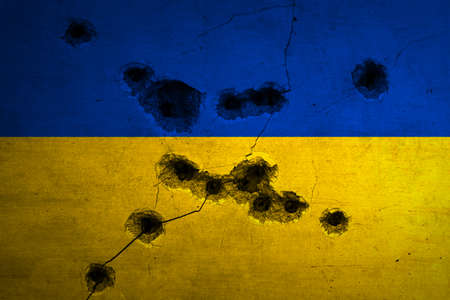 Military conflict in Ukraine background. Flag with bullet holes and cracks on concrete wall. Russian concept aggressionの写真素材