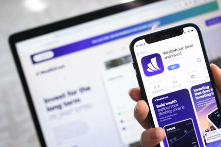 Poltava, Ukraine - April 5, 2022: Wealthfront Invest app icon. Hand with mobile phone with application. Mobile banking and investment conceptのeditorial素材