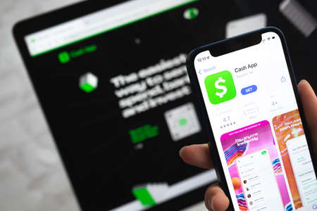 Poltava, Ukraine - April 5, 2022: Cash app icon. Hand with mobile phone with application. Mobile banking and investment conceptのeditorial素材