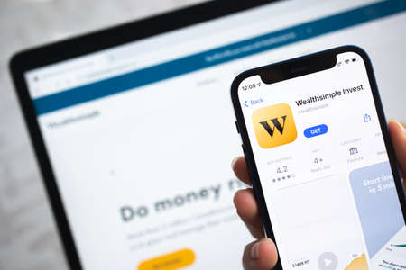 Poltava, Ukraine - April 5, 2022: Wealthsimple Invest app icon. Hand with mobile phone with application. Mobile banking and investment conceptのeditorial素材