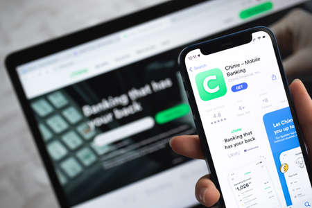 Poltava, Ukraine - April 5, 2022: Chime app icon. Hand with mobile phone with application. Mobile banking and investment conceptのeditorial素材