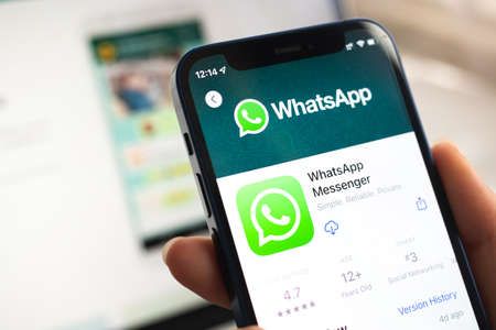 Poltava, Ukraine - April 5, 2022: Whatsapp app icon. Hand with mobile phone with application. Messenger and social networking conceptのeditorial素材