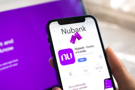 Poltava, Ukraine - April 5, 2022: Nubank app icon. Hand with mobile phone with application. mobile banking conceptのeditorial素材