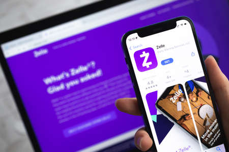 Zelle app icon. Hand with mobile phone with application. Mobile banking and investment concept photoのeditorial素材